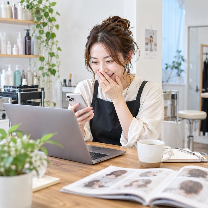 パソコンとスマートフォンでAIを試し、便利さに驚くオーナーのイメージ
