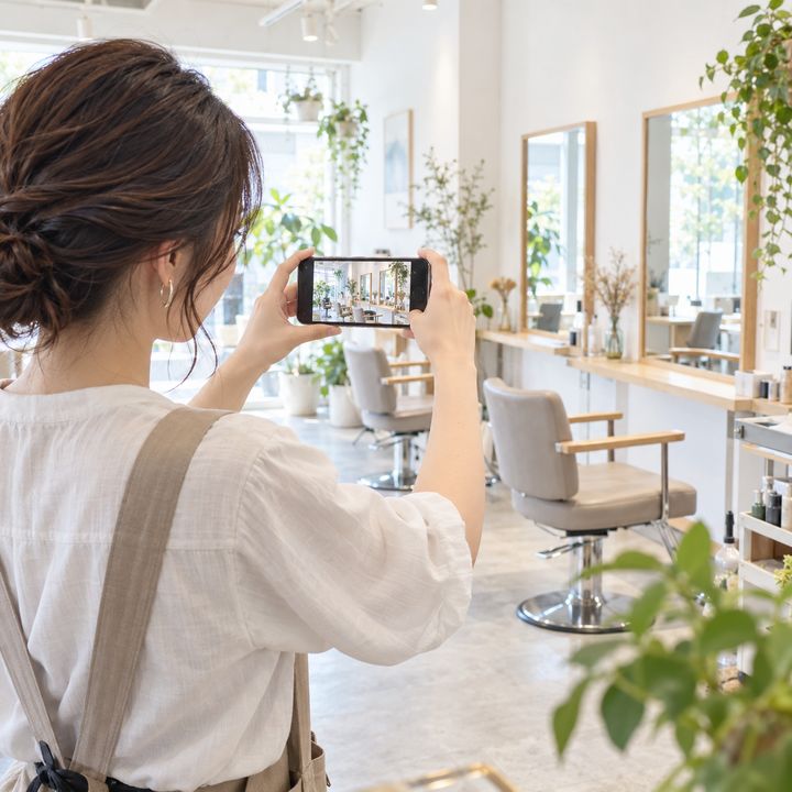 SNSに載せる店内の写真をスマートフォンで撮影するオーナーのイメージ